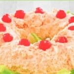 Orange fluff jello salad topped with maraschino cherries.