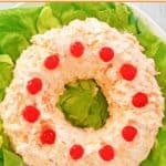 Orange fluff jello salad garnished with cherries.