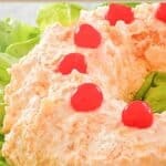Homemade orange fluff jello salad garnished with maraschino cherries.