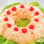 Orange fluff jello salad over butter lettuce leaves on a platter.