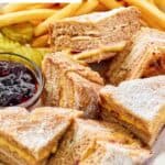 Homemade Bennigan's monte cristo on a platter with jam and fries.