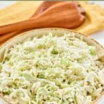 Homemade Brookville Hotel coleslaw in a serving bowl and wooden salad servers on a cloth napkin.