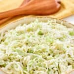 Homemade Brookville Hotel coleslaw in a large bowl and wooden salad servers behind it.