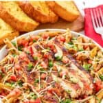 A plate of homemade Chili's cajun chicken pasta and garlic bread slices.