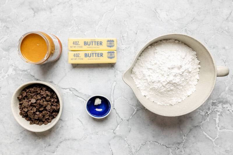 Homemade chocolate peanut butter balls ingredients on a marble surface.