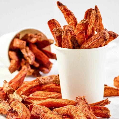Copycat Five Guys Cajun fries served in large cups and on parchment paper.