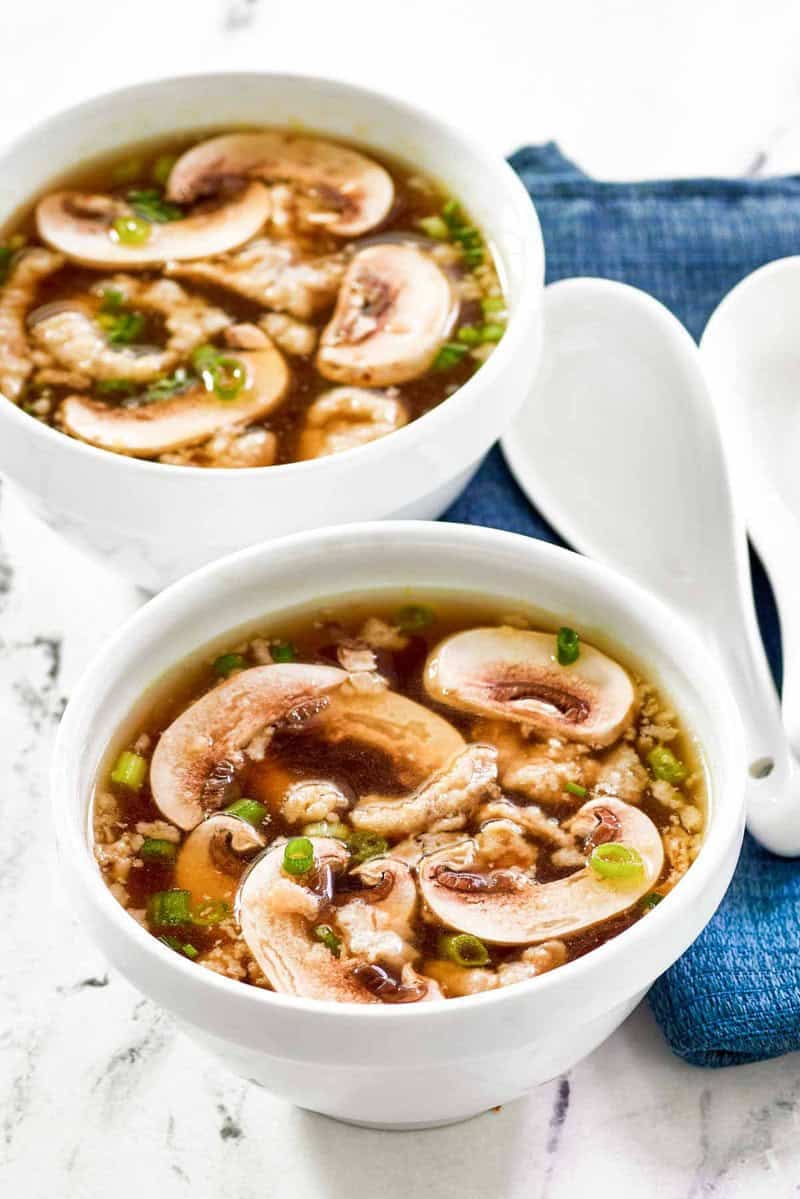 Homemade Japanese clear soup in two bowls and two soup spoons beside them.