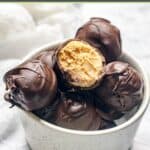Peanut butter balls in a small bowl on a marble surface.