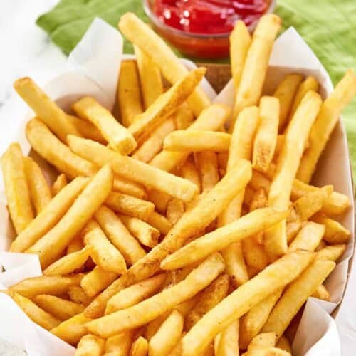 Copycat Wingstop seasoned French fries and a small cup of ketchup.
