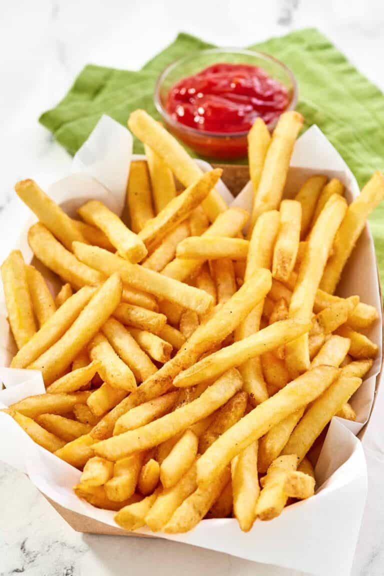 Copycat Wingstop seasoned French fries and a small cup of ketchup.
