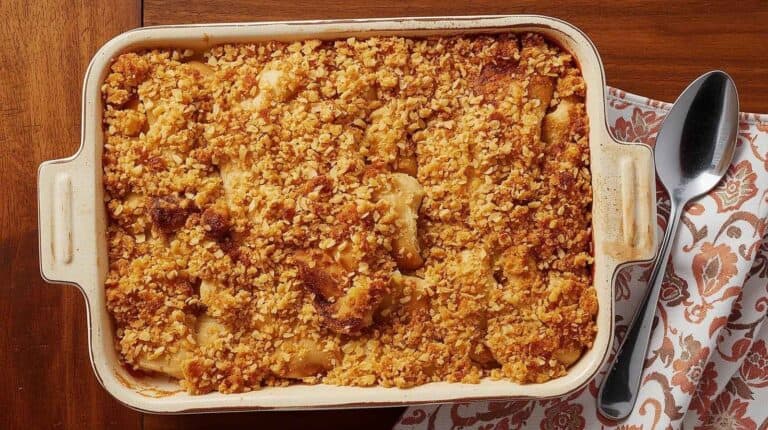 A chicken casserole with breadcrumb topping in a retro casserole dish on a wooden table.