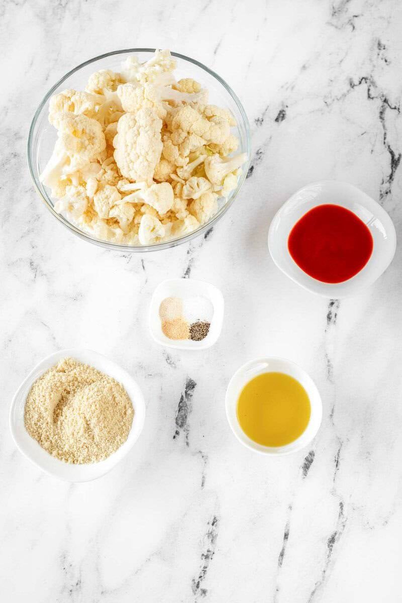 Air fryer buffalo cauliflower ingredients on a marble surface.