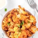 Air fryer buffalo cauliflower in a bowl and a fork next to it.