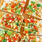 Homemade crescent roll veggie pizza on a wooden cutting board.