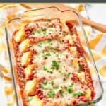 Homemade four cheese manicotti, a wooden spatula, and a kitchen towel.