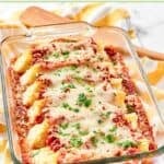 Homemade four cheese manicotti in a baking dish on top of a kitchen towel.