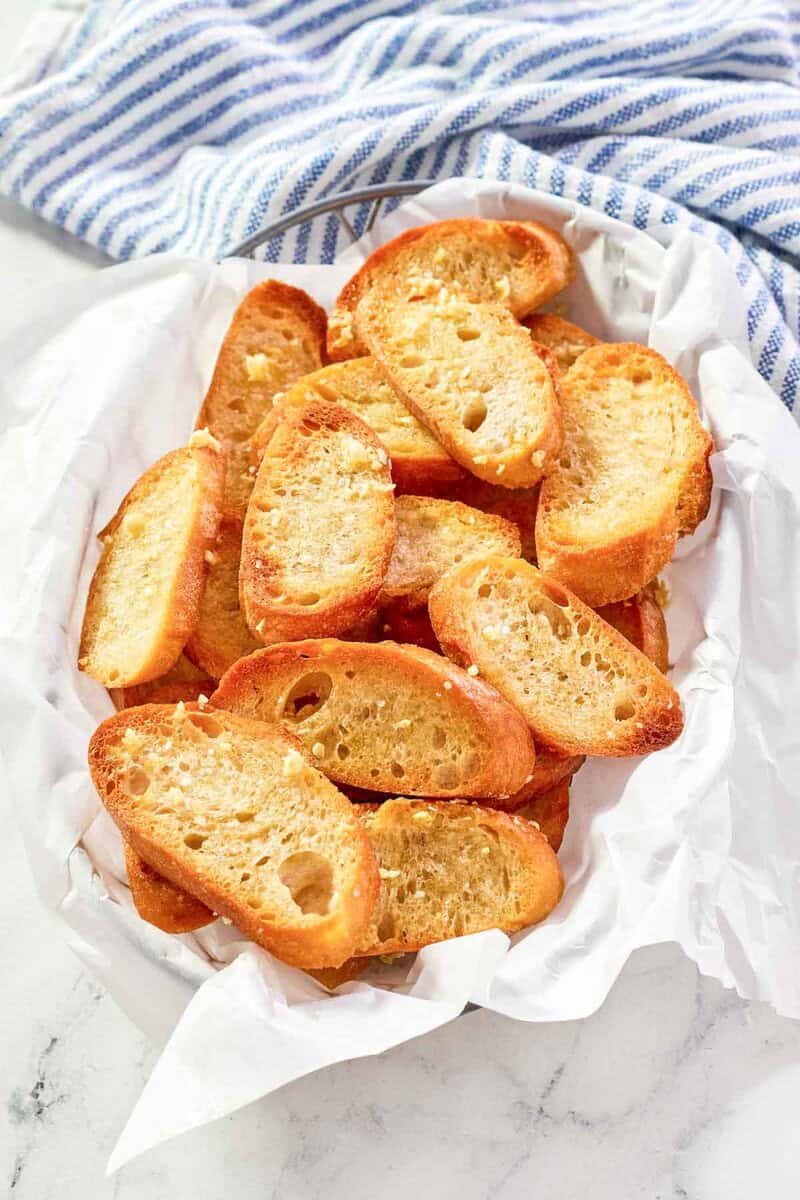 Homemade Jason's Deli garlic toast in a serving basket on a marble surface.