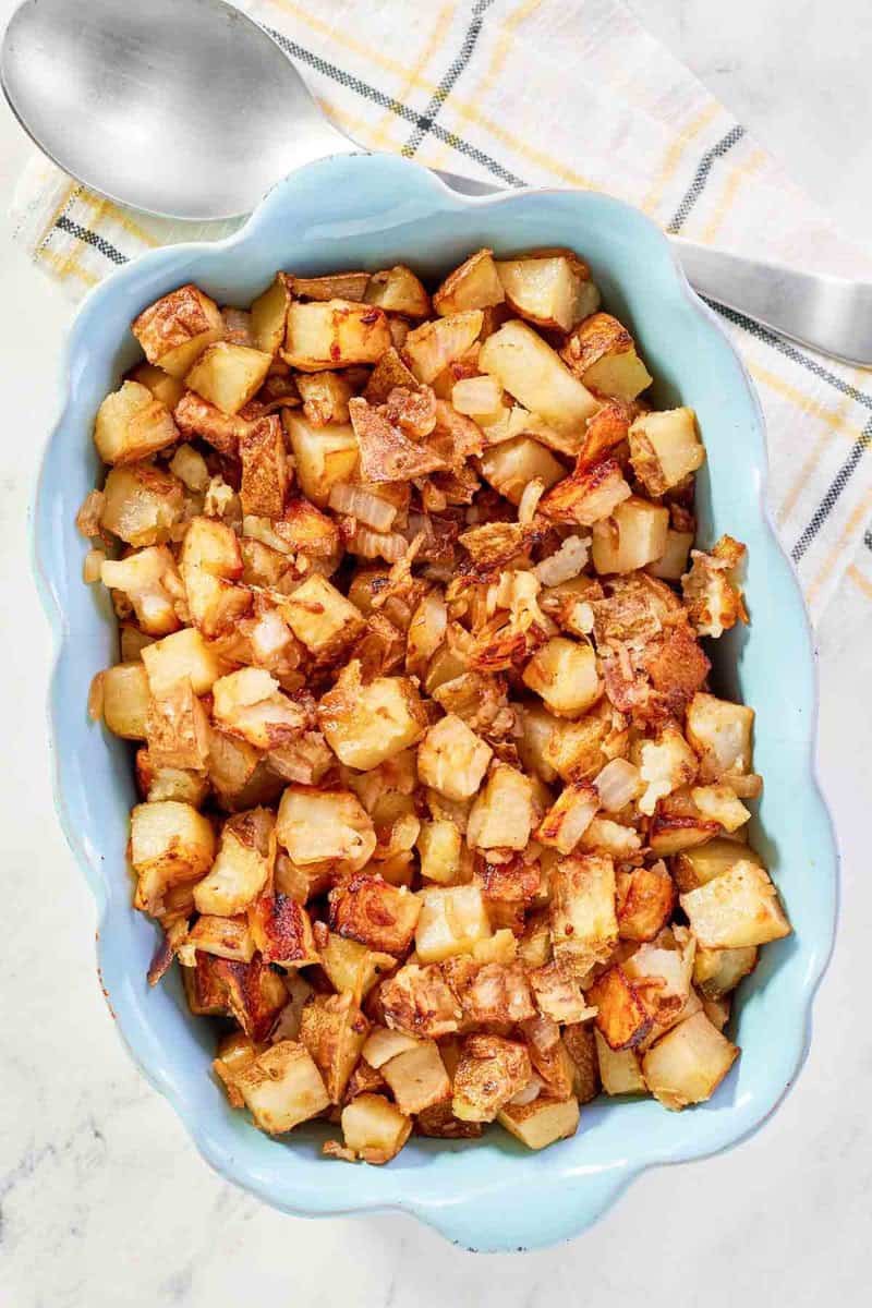 Lipton onion soup mix roasted potatoes in a serving dish and a serving spoon on a kitchen towel.