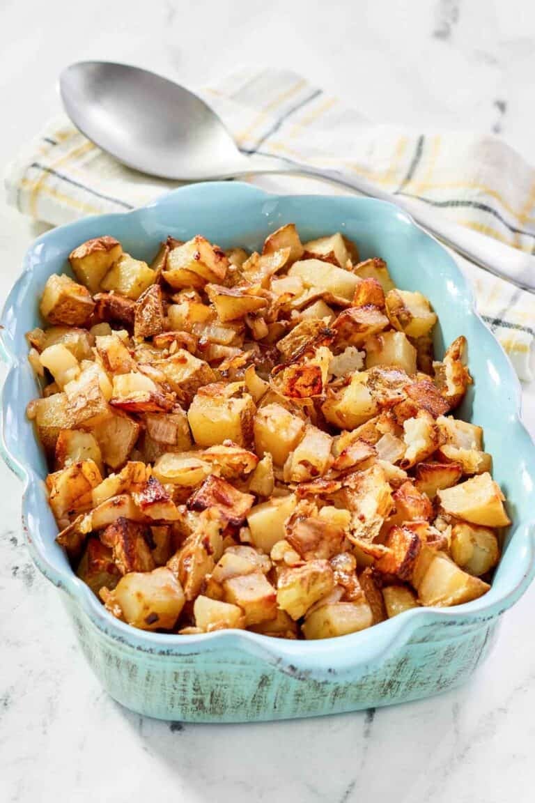 Lipton onion soup mix roasted potatoes in a serving dish and a serving spoon behind it.