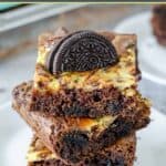 Homemade Oreo brownies in a stack and an Oreo cookie pressed into the top one.