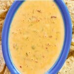 Spicy Rotel cheese dip in an oval serving dish and tortilla chips around it.
