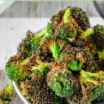 A bowl of air fryer broccoli on a wood surface.