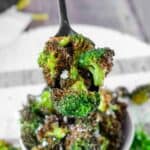 Air-fried broccoli on a spoon over a bowl of it.
