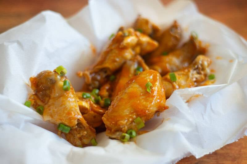 Air fryer garlic buffalo chicken wings in a parchment paper lined serving basket.