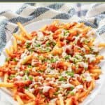 A platter of homemade buffalo fries and a kitchen towel by it.