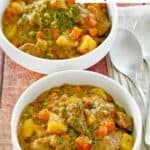 Two bowls of beef stew that was made in a Dutch oven.