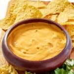 A bowl of green chile queso dip served with tortilla chips.