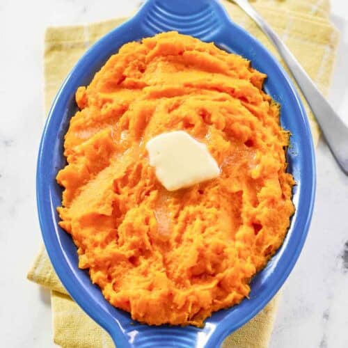 Horseradish mashed sweet potatoes is a serving dish and a spoon next to it.