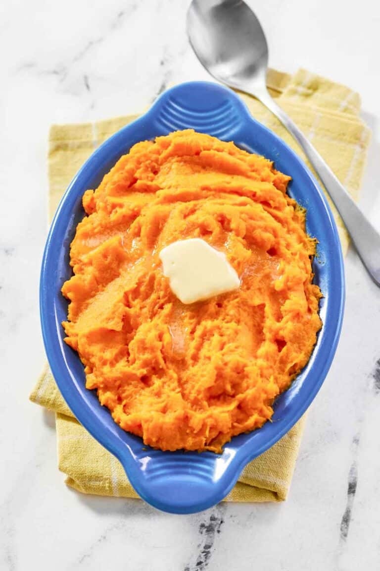 Horseradish mashed sweet potatoes is a serving dish and a spoon next to it.