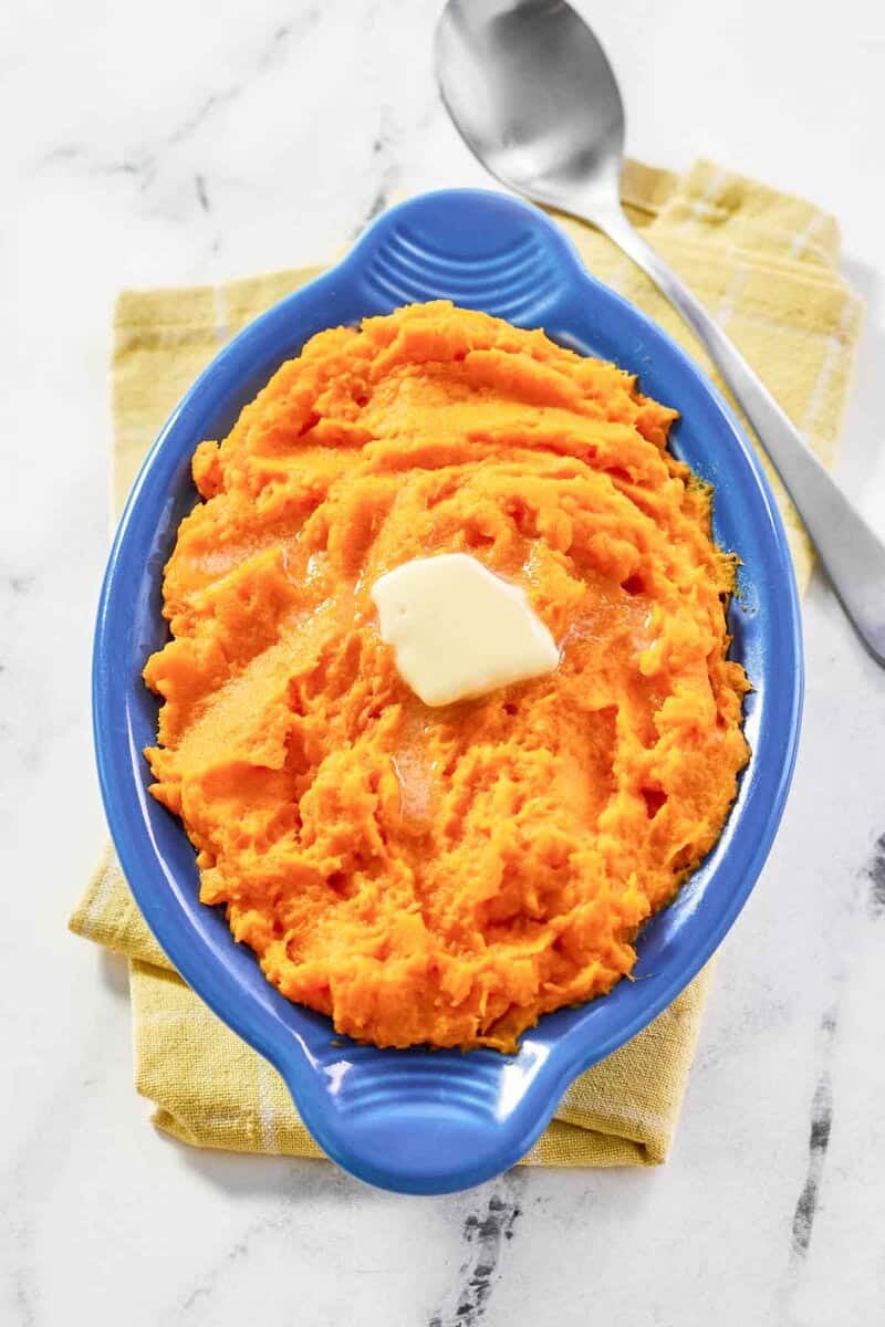 Horseradish mashed sweet potatoes is a serving dish and a spoon next to it.