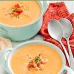 Crawfish bisque in soup crocks and two spoons next to them.