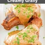 Two pan-fried pork chops topped with creamy gravy.