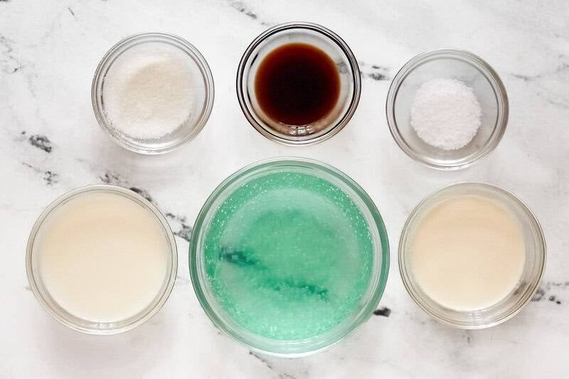 Ingredients for dirty soda including Baja Blast, heavy cream, milk, sugar, vanilla, and salt in glass bowls.