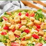 Homemade Texas Roadhouse house salad, salad tongs, and a kitchen towel.