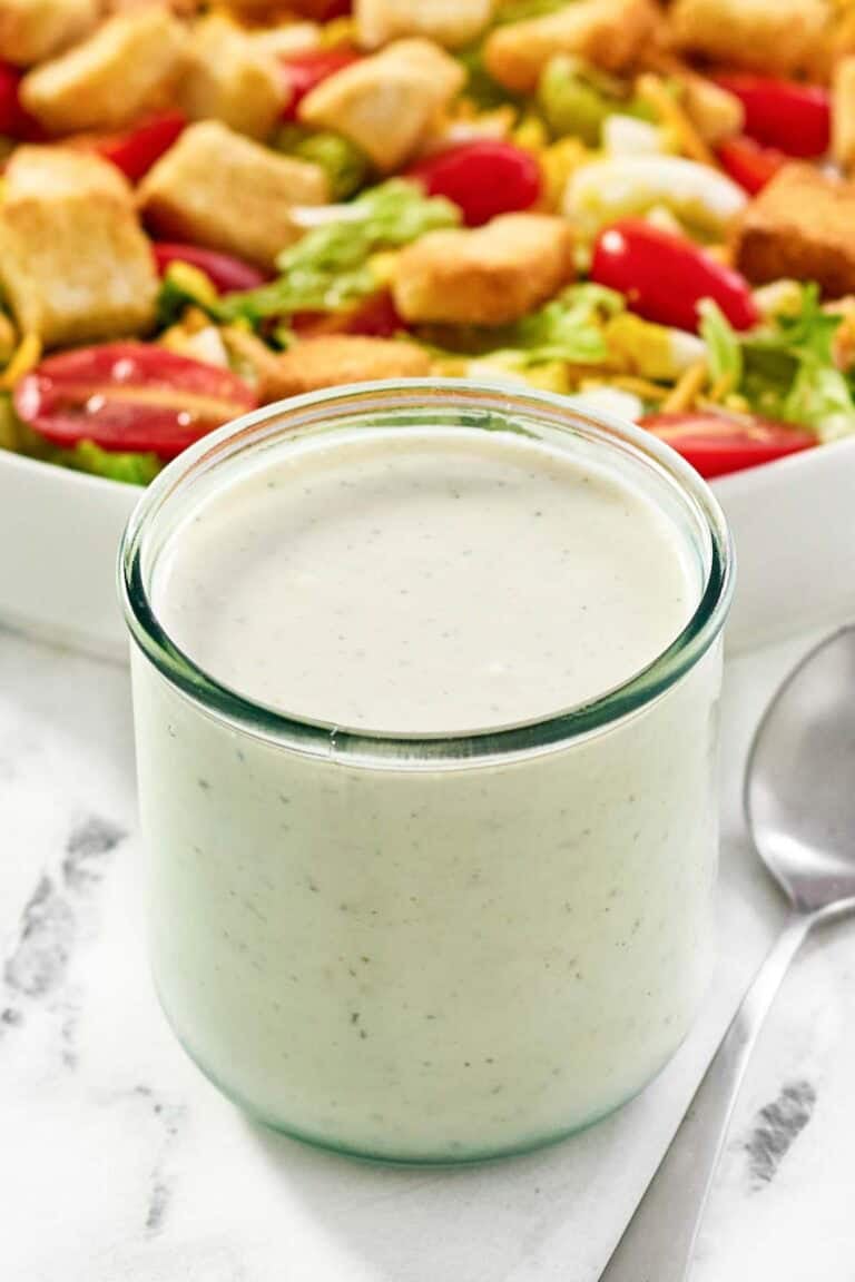 Copycat Texas Roadhouse ranch dressing in a jar and a salad behind it.
