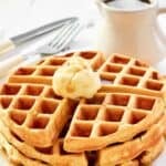 Fluffy buttermilk waffles served with butter and syrup for breakfast.