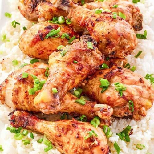 Baked and glazed chicken drumsticks served on top of rice and garnished with green onions.