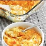 A bowl of cheesy hashbrown casserole with cornflake topping.