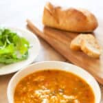 A bowl of chicken gumbo with rice, salad, and bread.