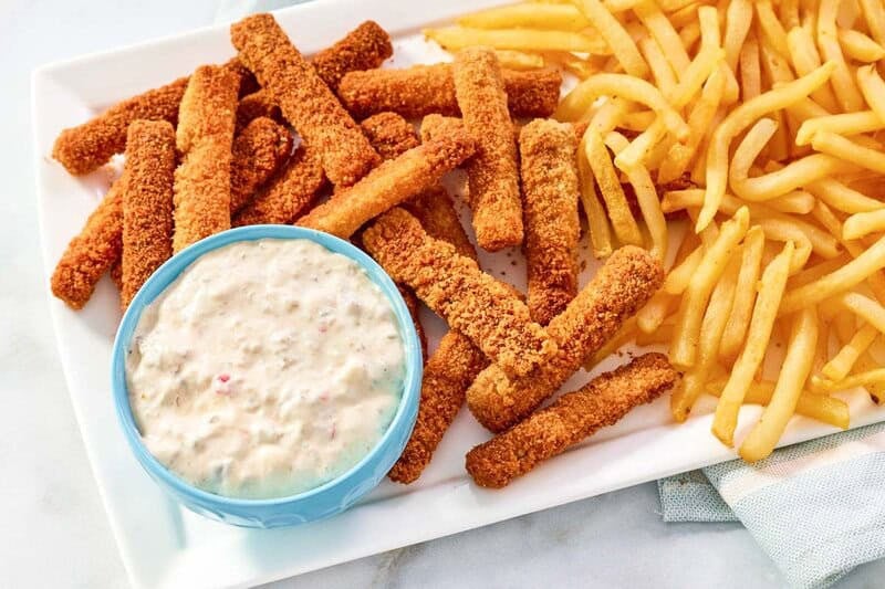 Fish sticks and fries served with tartar sauce.