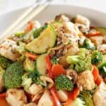 A bowl of stir-fried chicken and vegetables with Hunan sauce.