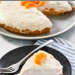 A prepared cheesecake with mandarin oranges with a slice cut out of it.