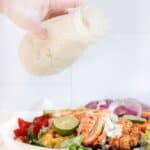 Pouring creamy salsa verde dressing on a fajita chicken salad.