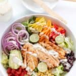 A bowl of homemade chicken fajita salad topped with creamy salsa verde dressing.