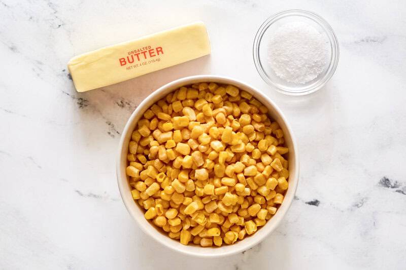 Frozen sweet corn kernels, a stick of butter, and salt in a small bowl.