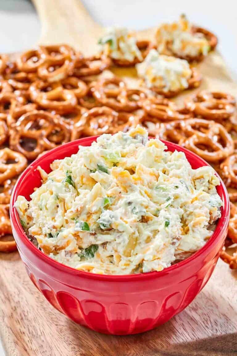 A bowl of creamy cheddar bacon dip served with mini pretzels.